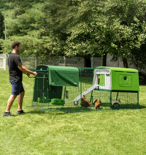 Mand flytter Eglu Cube transportabelt hønsehus med hjul og håndtag