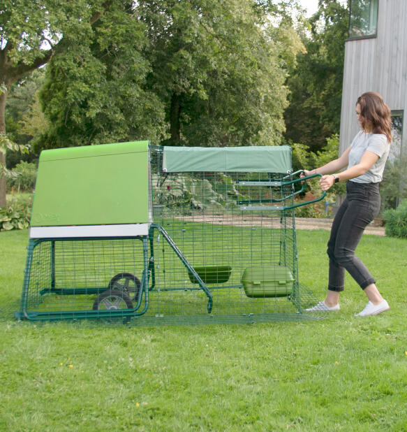 Kvinde flytter Eglu Go transportabelt hønsehus i sin baghave